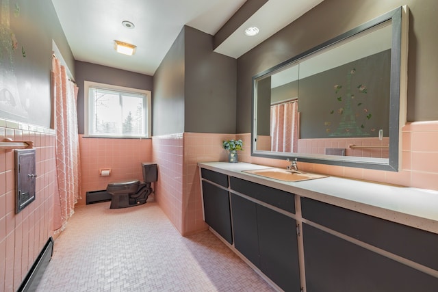 bathroom with tile walls, wainscoting, vanity, a baseboard heating unit, and toilet
