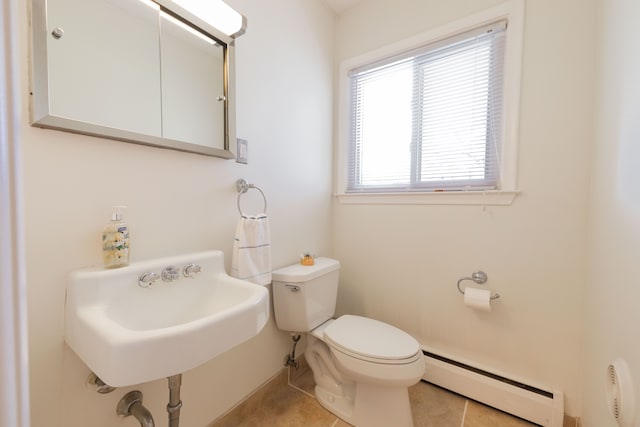 half bathroom featuring a sink, toilet, tile patterned floors, baseboards, and a baseboard radiator