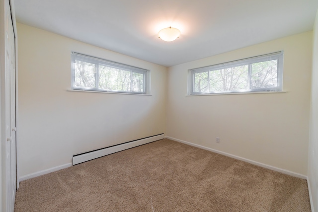 carpeted spare room with baseboards and a baseboard heating unit
