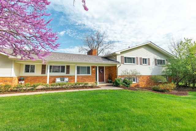 split level home featuring brick siding, a front lawn, and a chimney