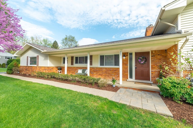 ranch-style house with brick siding, a front yard, and a chimney