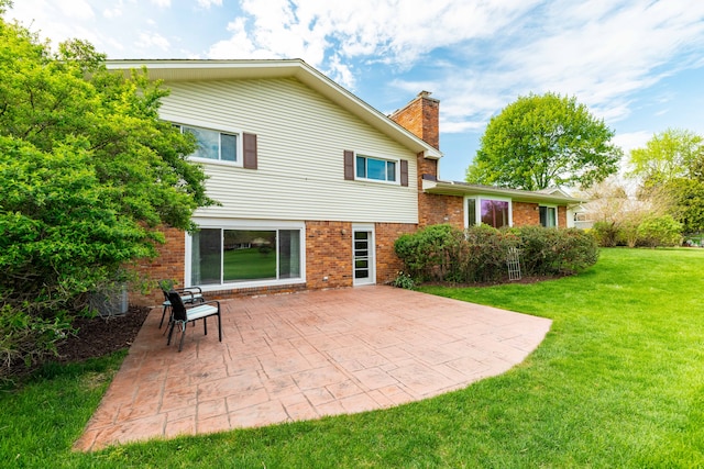 back of property featuring a patio, brick siding, a lawn, and a chimney