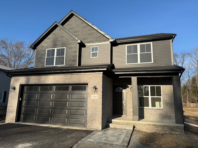 view of front facade featuring aphalt driveway, brick siding, and a garage