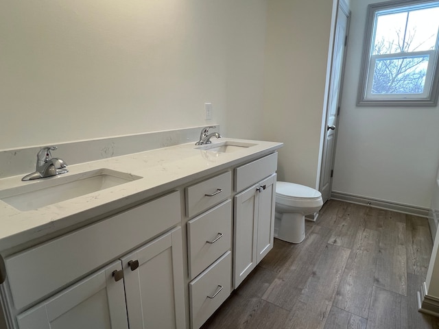 full bathroom featuring double vanity, wood finished floors, toilet, and a sink