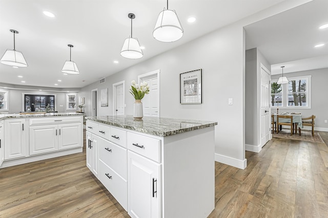 kitchen with baseboards, light wood-type flooring, white cabinets, and light stone counters