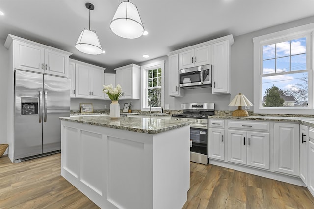 kitchen with recessed lighting, white cabinets, a kitchen island, and stainless steel appliances