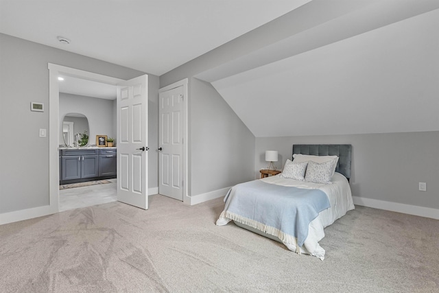 bedroom with arched walkways, vaulted ceiling, light colored carpet, and baseboards