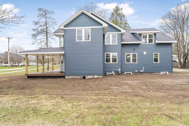 rear view of property with a yard and roof with shingles