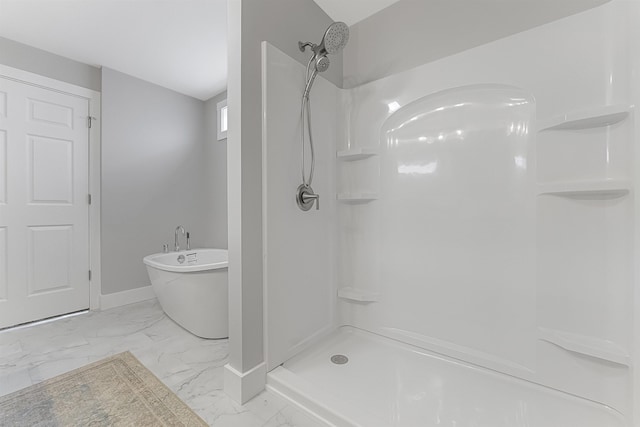 full bathroom featuring marble finish floor, a freestanding tub, a shower, and baseboards