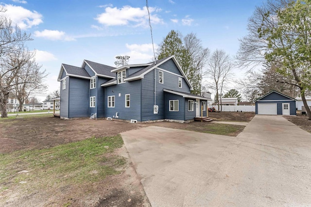 exterior space featuring an outdoor structure, a detached garage, entry steps, and concrete driveway