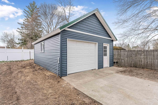 detached garage featuring fence and concrete driveway