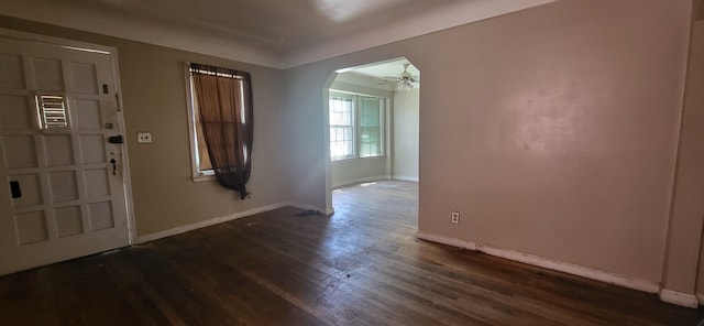 foyer entrance with arched walkways, baseboards, a ceiling fan, and dark wood-type flooring
