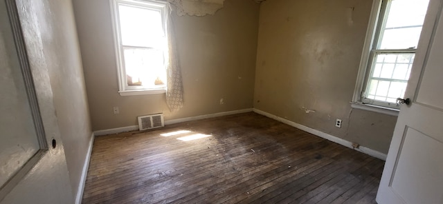 empty room featuring visible vents, baseboards, and hardwood / wood-style flooring