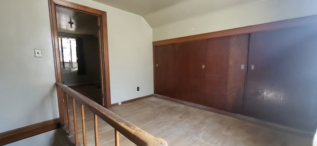 hall featuring concrete flooring, baseboards, and an upstairs landing
