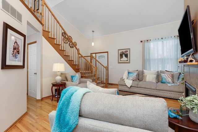 living area with stairway, wood finished floors, baseboards, and a fireplace