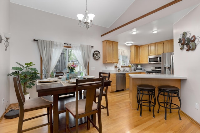 dining area with vaulted ceiling, a chandelier, light wood-type flooring, and healthy amount of natural light