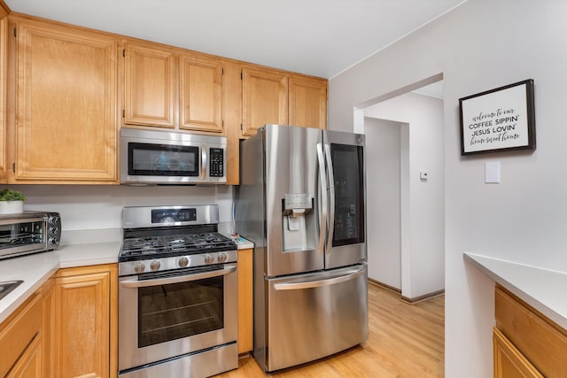 kitchen featuring appliances with stainless steel finishes, light countertops, and light wood-style floors