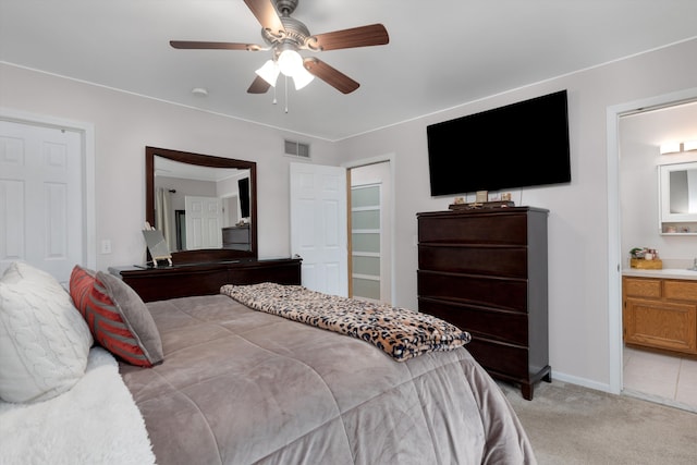 bedroom with light colored carpet, ensuite bath, ceiling fan, and baseboards