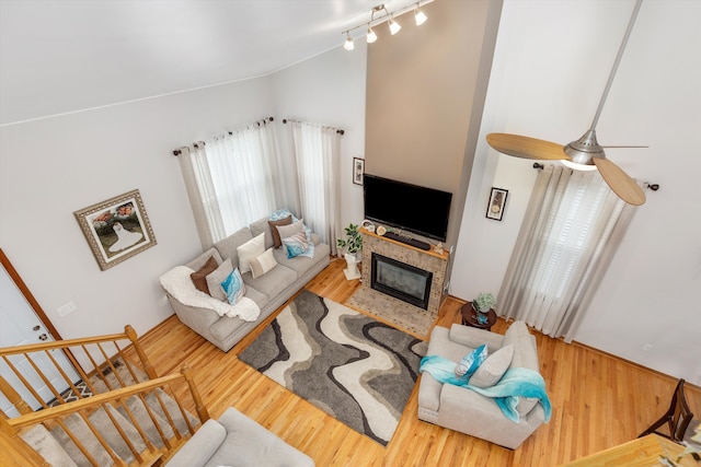 living room with stairs, a ceiling fan, wood finished floors, a fireplace with flush hearth, and lofted ceiling