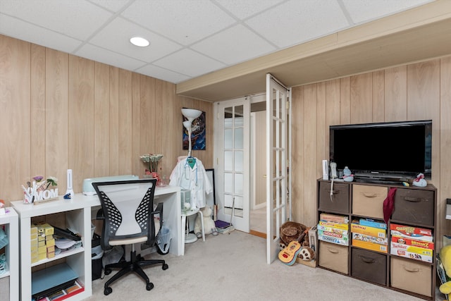 office space with wood walls, carpet flooring, and a drop ceiling
