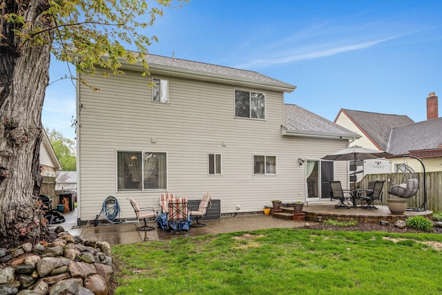back of property featuring a patio, a lawn, and roof with shingles