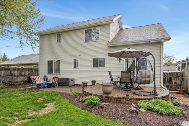 rear view of property with a patio area, central air condition unit, and a shingled roof