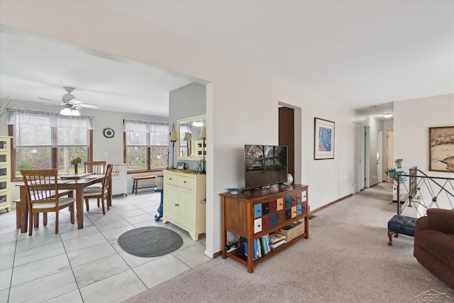 living room featuring baseboards, light tile patterned floors, and a ceiling fan