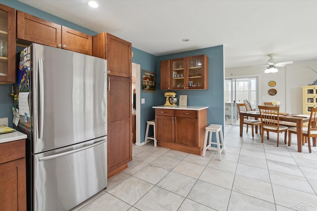 kitchen featuring a ceiling fan, brown cabinets, freestanding refrigerator, and light countertops