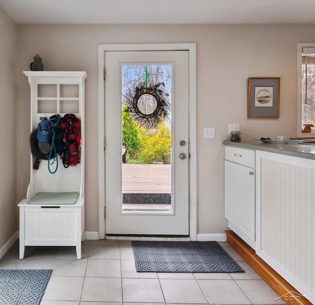 doorway featuring light tile patterned floors, a wealth of natural light, and baseboards