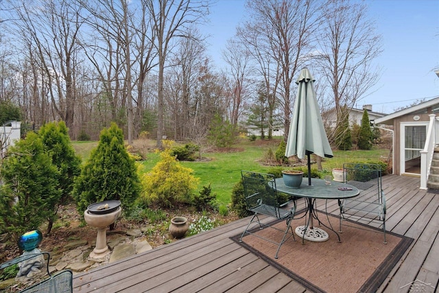 wooden deck with a lawn and outdoor dining area