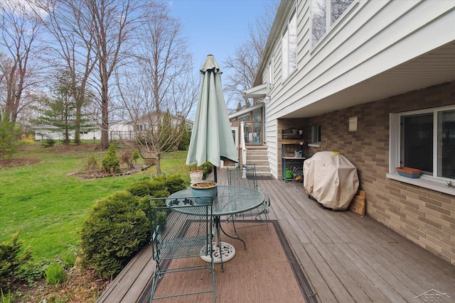 wooden terrace with outdoor dining space, grilling area, and a yard