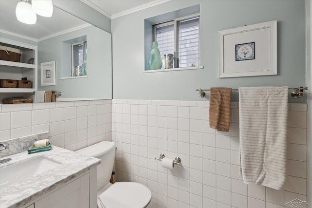 bathroom with a wainscoted wall, toilet, ornamental molding, tile walls, and vanity