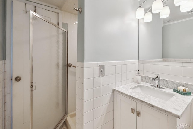 bathroom with a shower stall, visible vents, a wainscoted wall, tile walls, and vanity