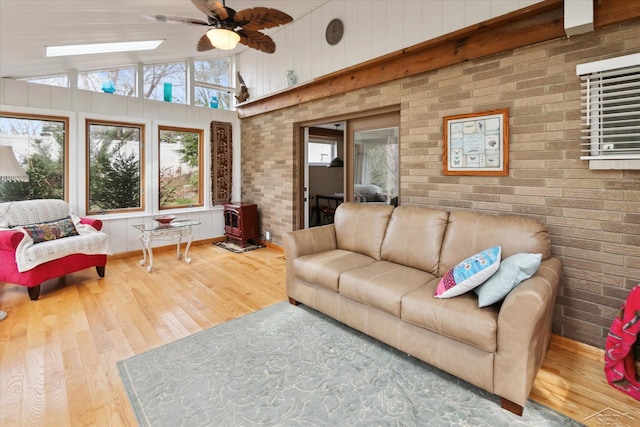 living area with ceiling fan, wood finished floors, and brick wall