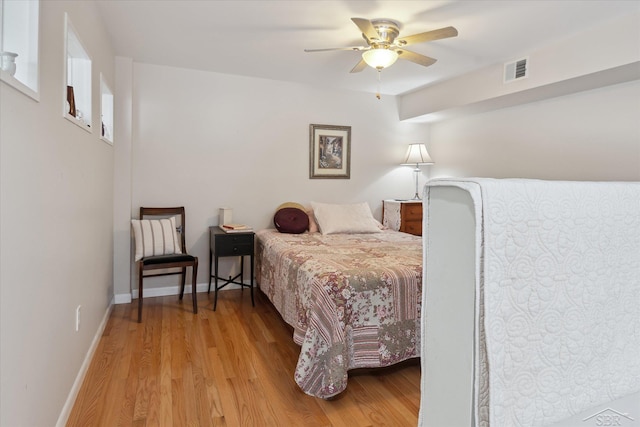 bedroom with wood finished floors, visible vents, ceiling fan, and baseboards