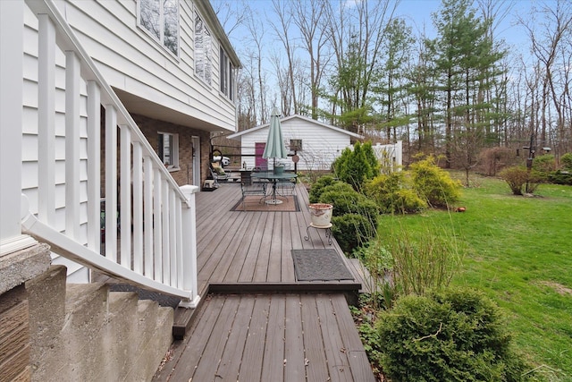 wooden terrace with outdoor dining space and a lawn