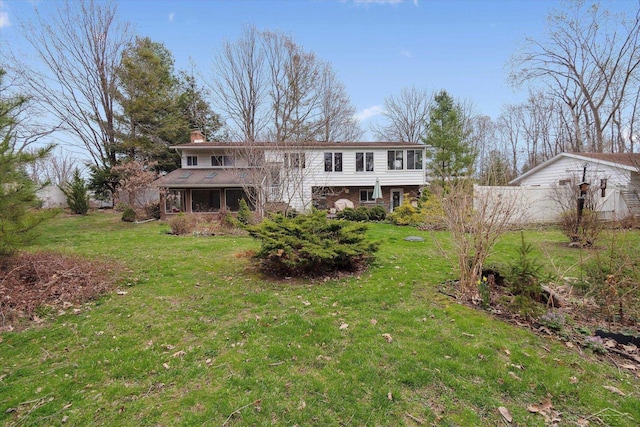 back of house with a chimney and a yard