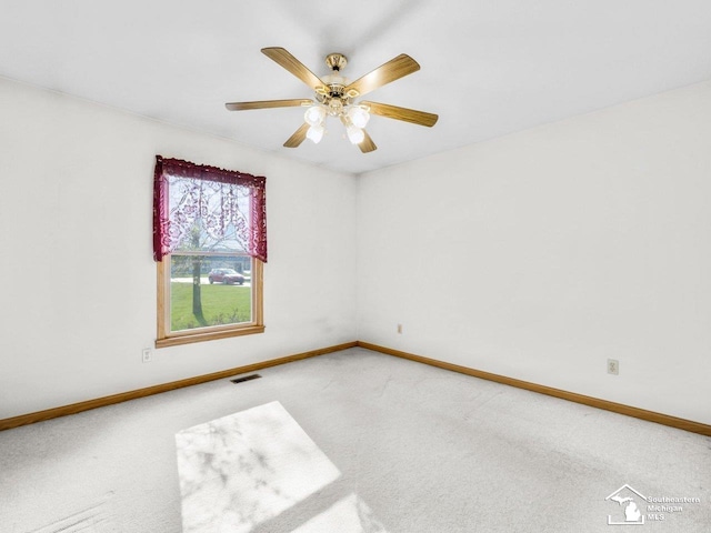carpeted empty room with visible vents, ceiling fan, and baseboards
