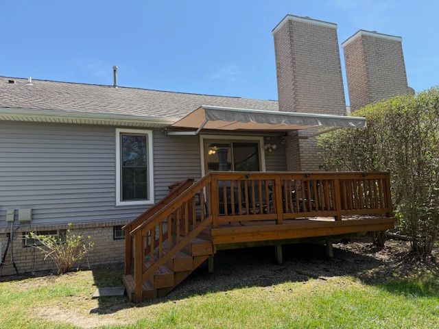 rear view of property featuring a deck, roof with shingles, and a chimney