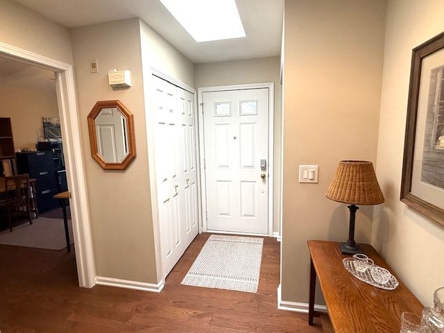 entrance foyer featuring a skylight, baseboards, and dark wood-type flooring