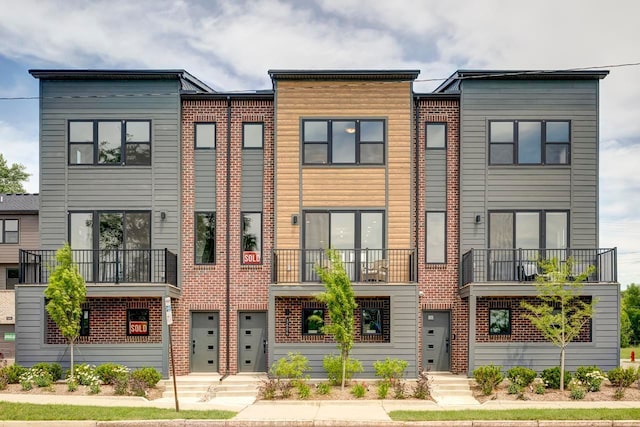 view of front facade featuring brick siding and a balcony