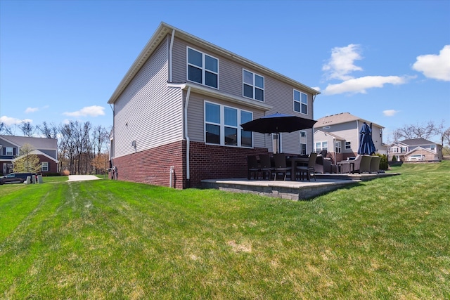 rear view of house featuring brick siding, a yard, a residential view, and a patio