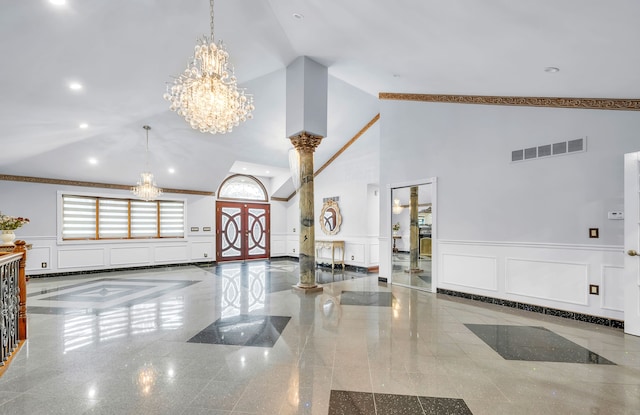 entryway with a notable chandelier, high vaulted ceiling, a wainscoted wall, visible vents, and a decorative wall