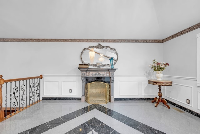 living room with wainscoting, granite finish floor, a fireplace, and a decorative wall