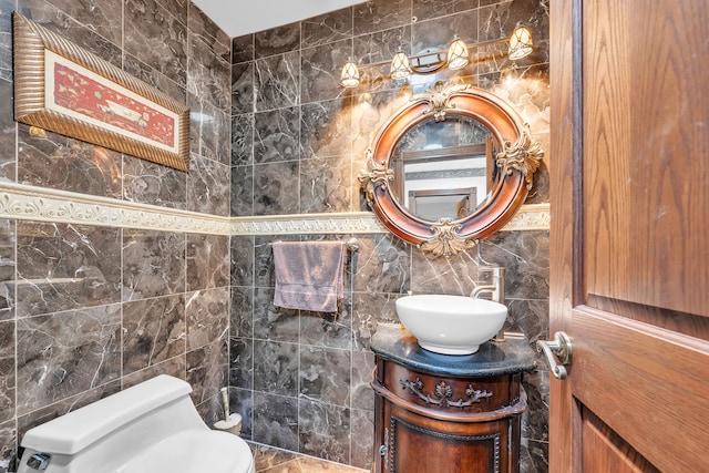 bathroom with toilet, vanity, and tile walls