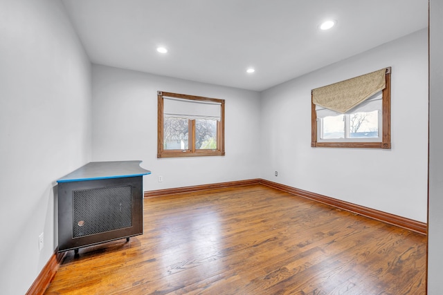 spare room featuring baseboards, wood finished floors, and a healthy amount of sunlight