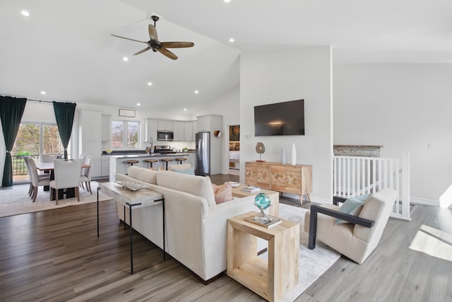 living room featuring light wood-type flooring, high vaulted ceiling, ceiling fan, and recessed lighting