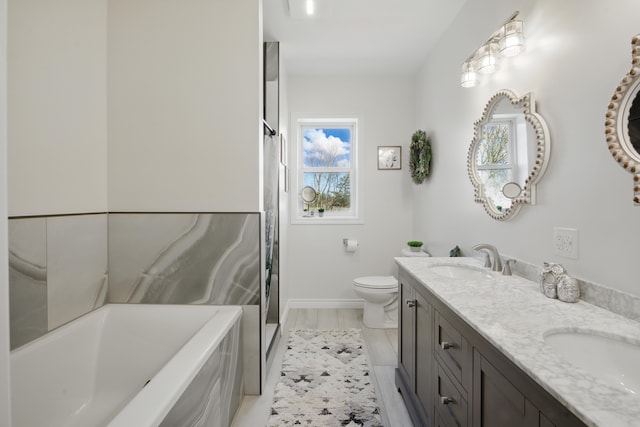 full bath featuring toilet, a sink, a tub, and baseboards