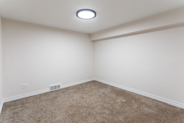 carpeted spare room with visible vents and baseboards