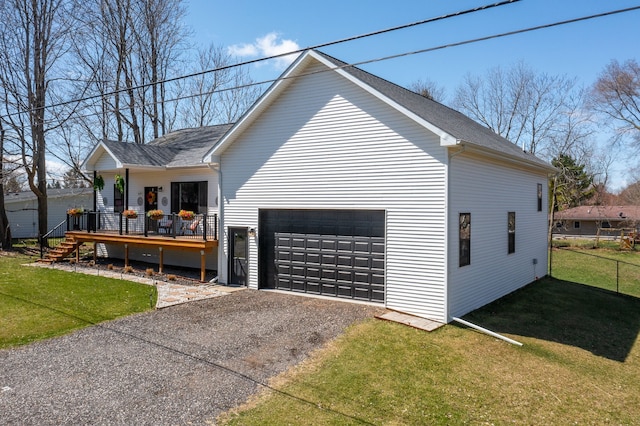 view of side of home featuring a lawn, roof with shingles, a deck, and fence